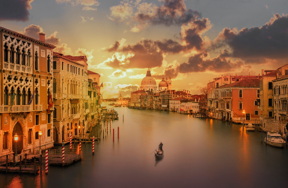 A lone gondolier cruising the Venice canals during sunset