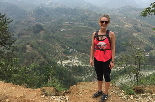  Flight Centre Travel Expert Cherie Horley stands on a mountainside in the northern Vietnamese region of Sapa, as terraced rice paddies unfold in the distance. 