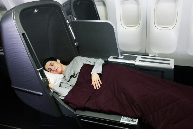 A Qantas passenger sleeping in a lay flat business class seat