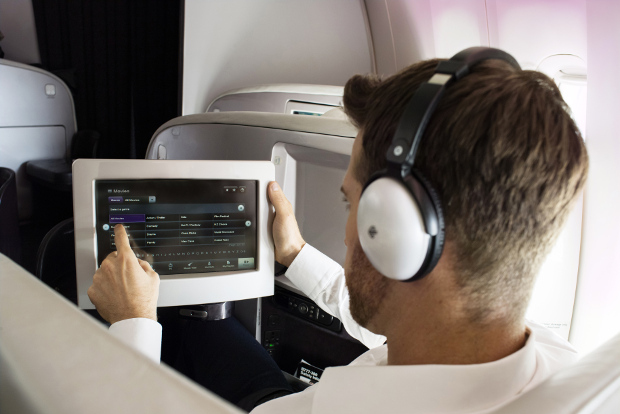 A man looking at the entertainment while wearing the headphones