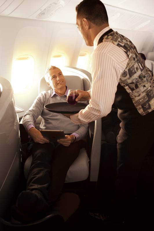 A flight attendant serving a passenger a drink