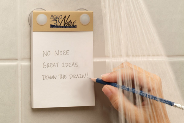 A person writing a note in the shower on the AquaNotes pad