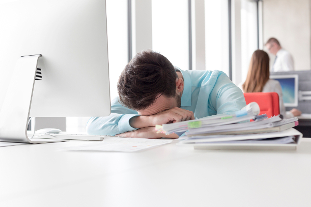 A man sitting at his desk with his head in his hands