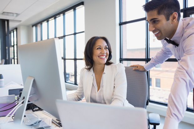 two office workers looking at computer and smiling