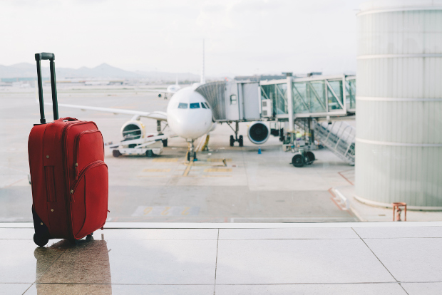 A rolling suitcase in front of a window overlooking the airport tarmac