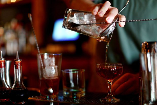 A person pouring a cocktail from a shaker