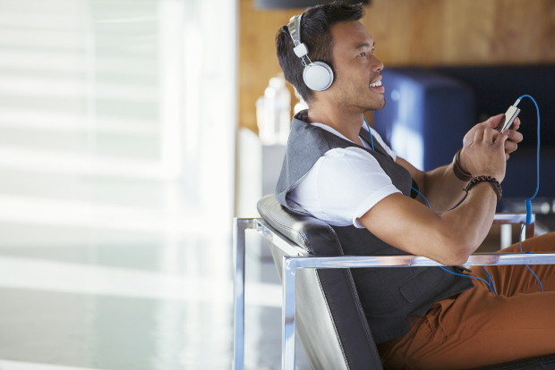 A young businessman listens to a podcast.
