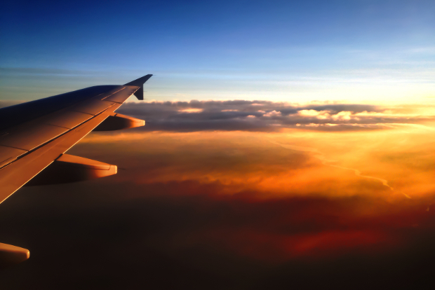 An airplane flying through the sky at dusk with golden and red clouds 