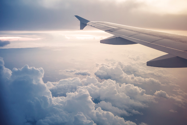 An airplane wing with clouds in the background