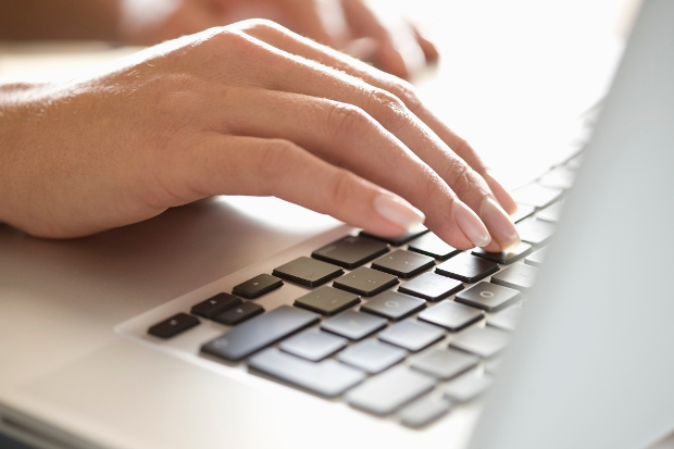 A close up of a woman's hands on a laptop keyboard