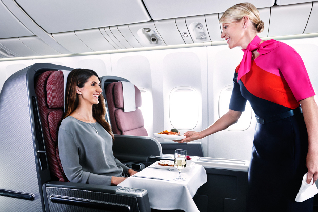 Flight attendant serves a female passenger a plate of food in business class