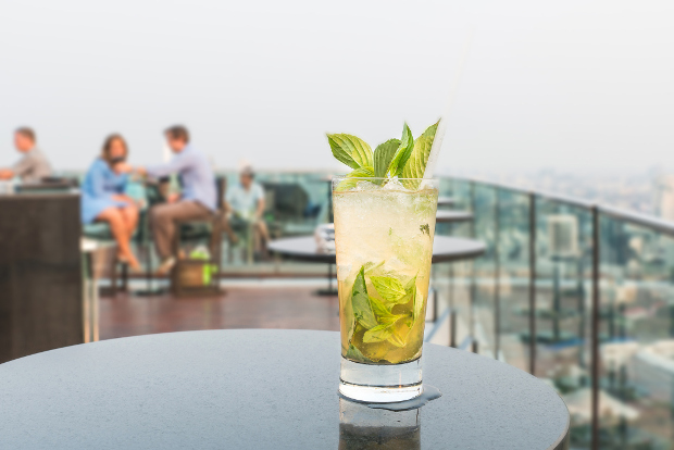 A cocktail sitting on a table at a rooftop bar