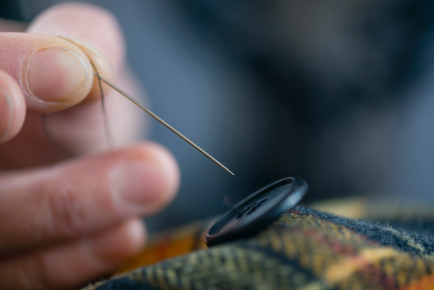 A man sews on a button.