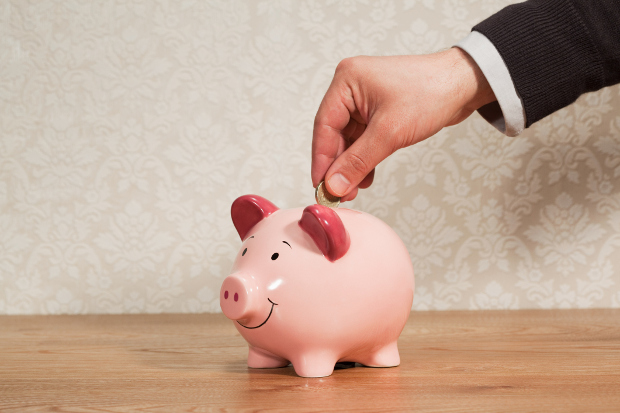 A man putting a coin in a piggy bank