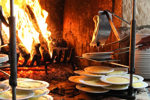 Cheese melts before an open fireplace for the Raclette course at Fireside Dining.