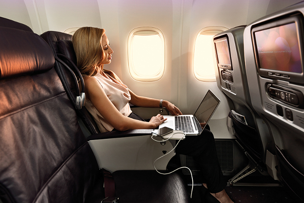 A woman sitting in business class using her laptop