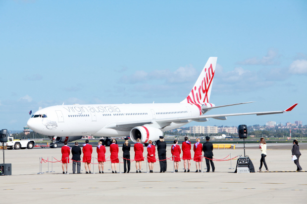 Virgin flight crew standing on the runway looking at a Virgin plane