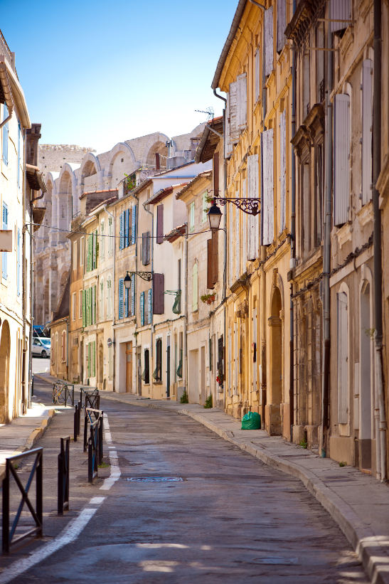 street lined with old houses in arles and amphitheatre in background