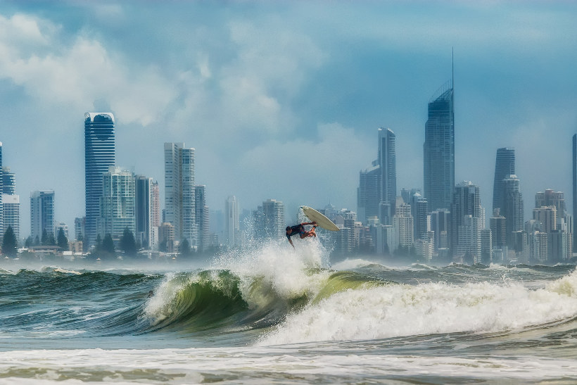 burleigh heads surfer on wave with skyline behind