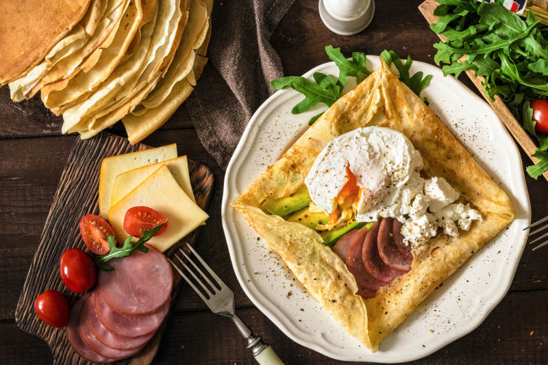 savoury crepe with ham, egg, cheese and sides on plate