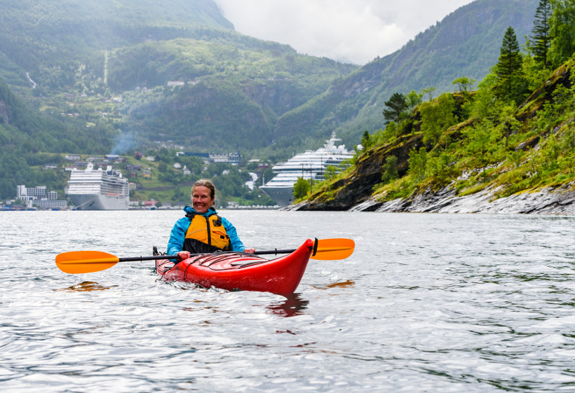 kayaker in fjord with cruise ship in background