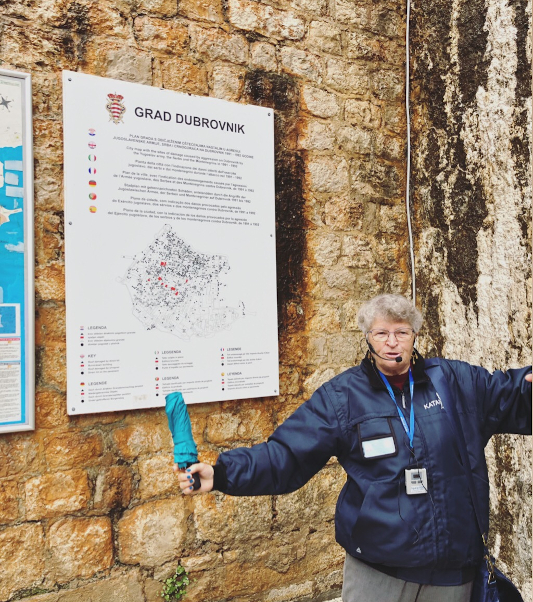 Aida standing in front of a map that shows the damage to the Old Town of Dubrovnik during the war