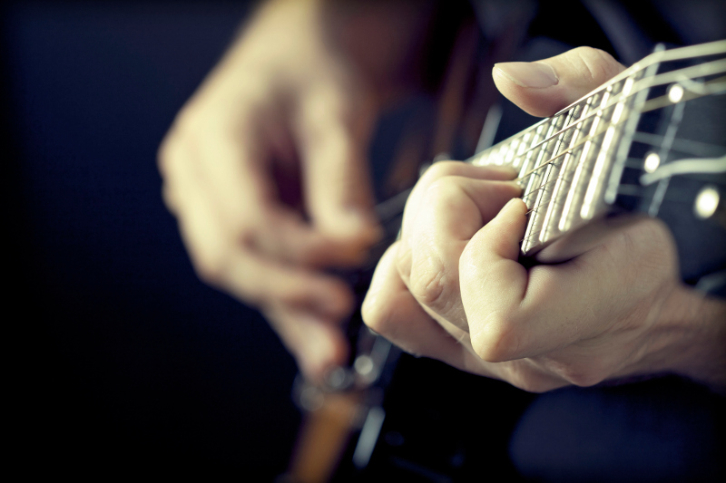 A close-up of a man playing guitar.