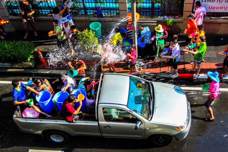 People in a ute throw buckets of water on a crowd during Songkran in Thailand.