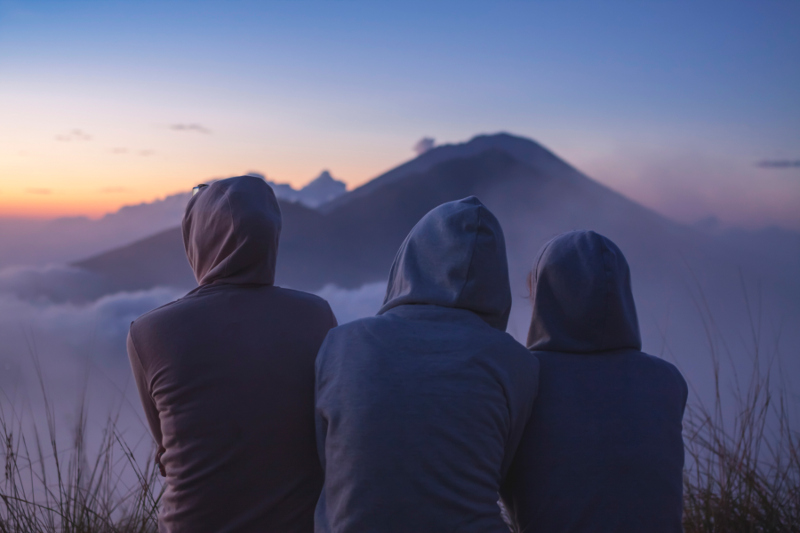 Three women seen from behind, awaiting sunrise at Mt Batur, Bali.
