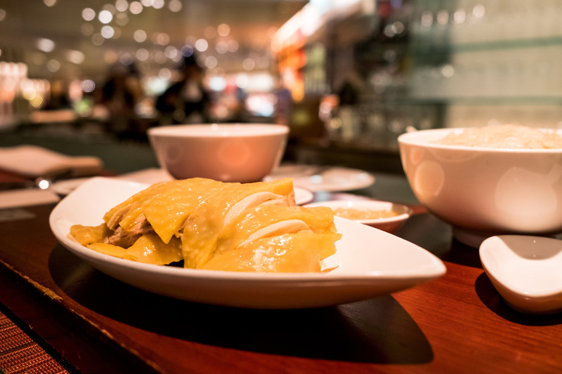 A close-up view of a plate of Hainanese chicken rice in a restaurant.