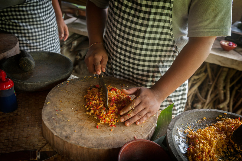 Hands chopping ingredients at a cooking class in Bali, Indonesia.