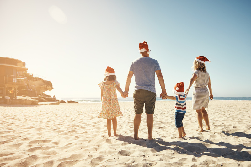 A family at the beach wears Santa hats.