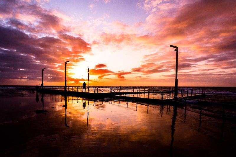 Sunset with a person on a pier.