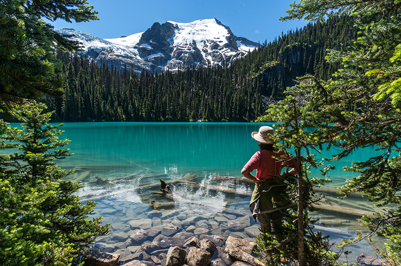 a woman looks over a blue lake in joffre lakes national park