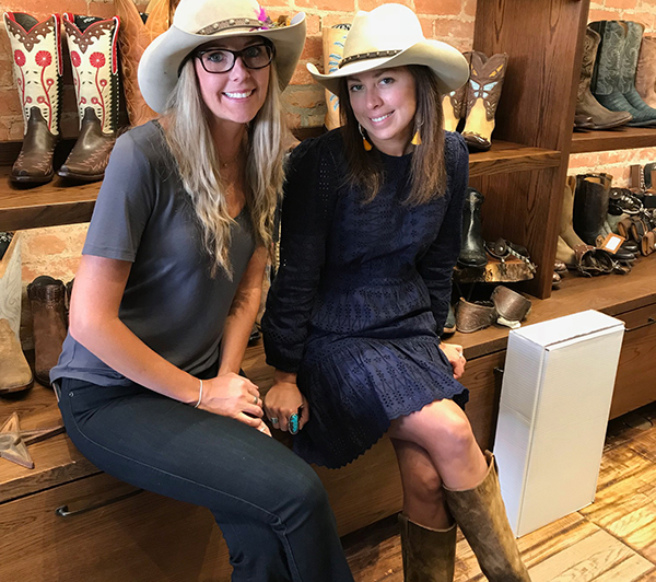Two women sit in front of cowboy boots at an Aspen store.