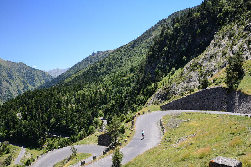 A lone cyclist navigates a winding mountain road in the Pyrenees, France.