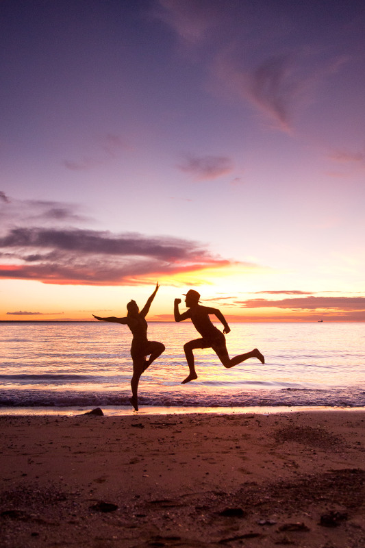 couple jumping on beach infront of sunset in darwin