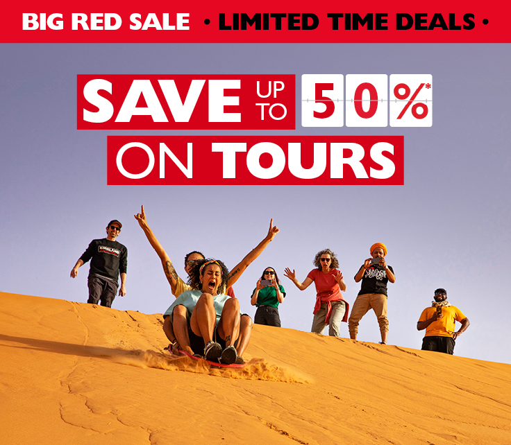 Save up to 50%* on tours. Two people sand tobogganing while others cheer them on
