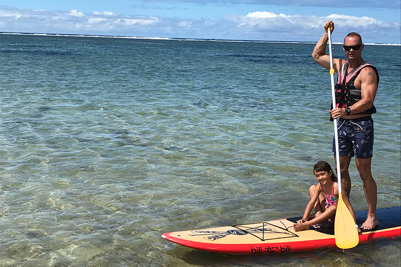 Father and daughter stand-up paddleboarding in Fiji