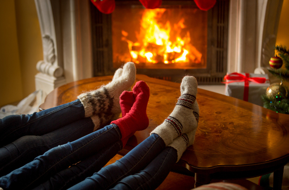 A group of friends warming their feet in front of a fireplace