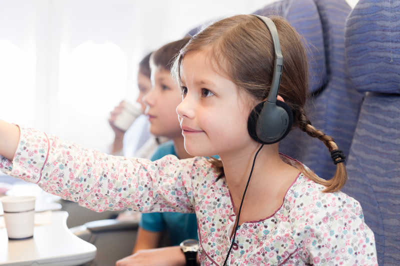 A young girl navigates the inflight entertainment on a plane.