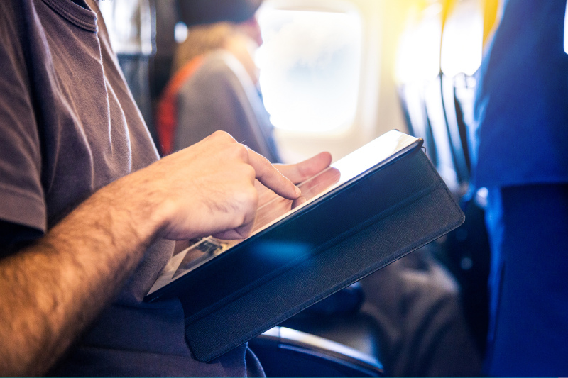 A man using a tablet on a plane