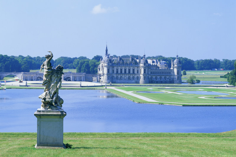 chantilly castle from afar with statue in foreground