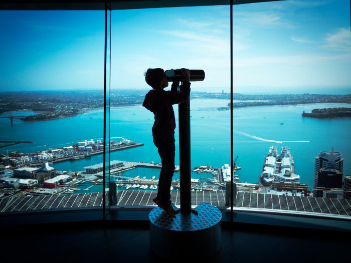 young boy looking through binoculars at auckland skytower