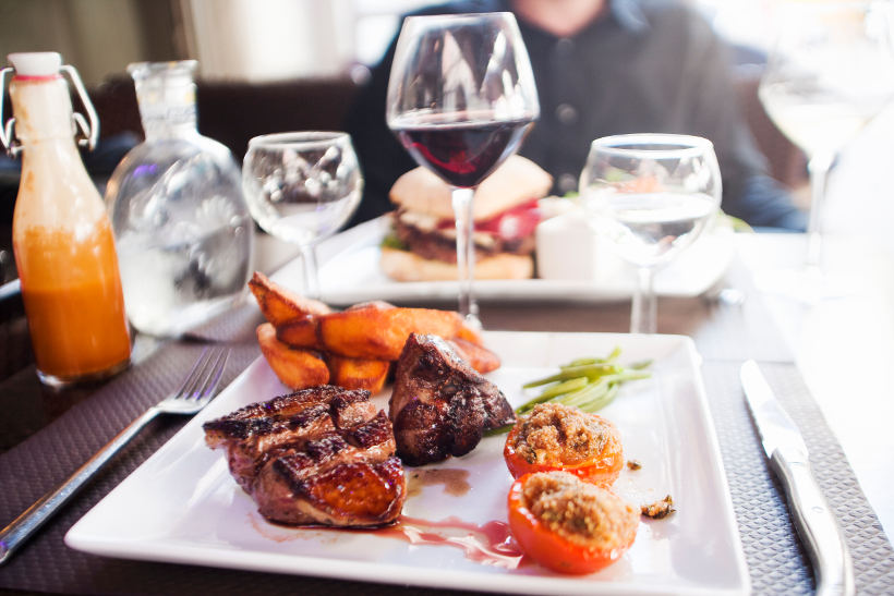 french steak and vegetable meal with red wine on table