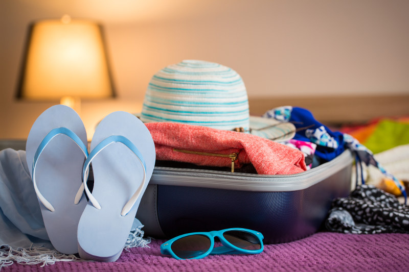 suitcase open in cruise ship cabin with hat, thongs spilling out