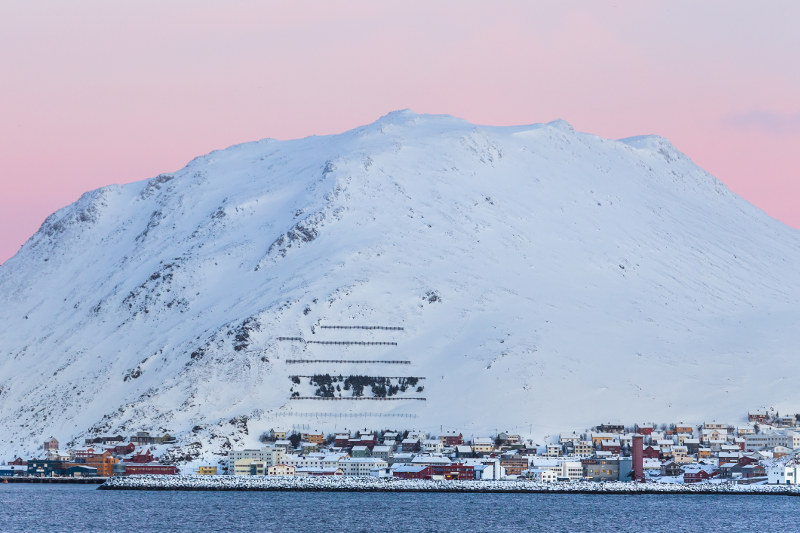 town with mountain behind covered in snow, pink twilight sky