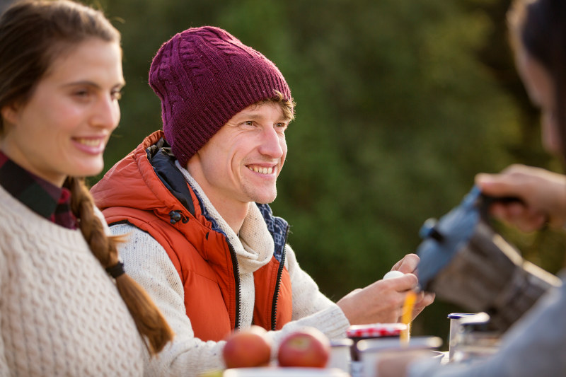man wearing beanie at table with friends