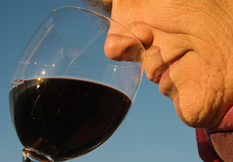 A close up of a man smelling a red wine