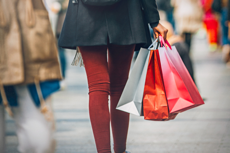 View of woman's legs and several shopping bags that she is carrying